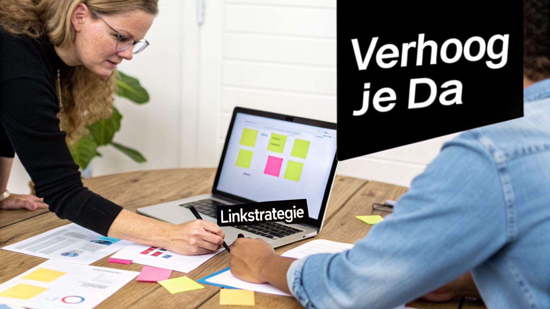 Twee mensen werken samen aan een linkstrategie om de Domain Authority te verhogen, met documenten en laptop.